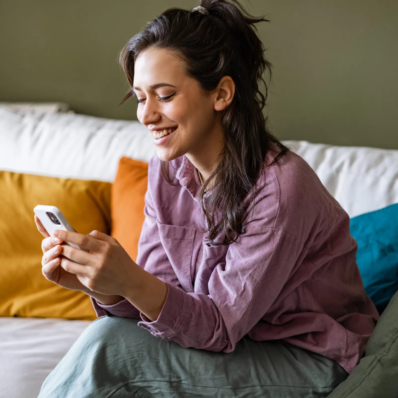 Zufriedene Mieterin schaut lächelnd auf ihr Smartphone